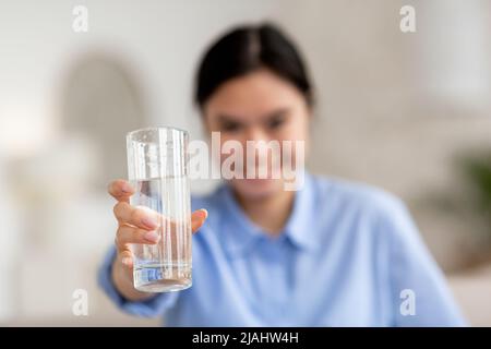 Fuoco selettivo sul vetro di acqua nella mano della donna asiatica Foto Stock