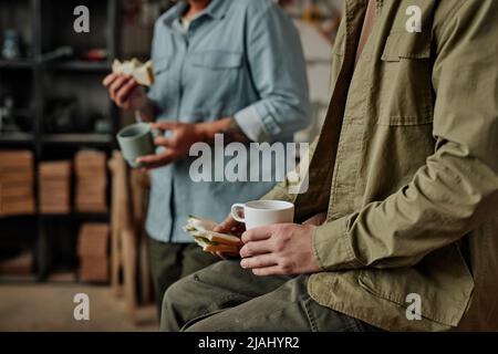 Primo piano di persone che si godono il pranzo con caffè durante la pausa in officina, spazio copia Foto Stock