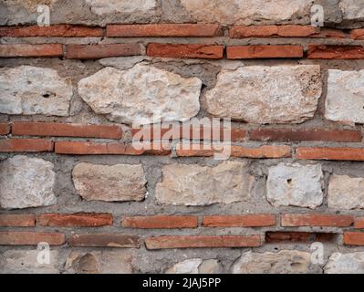 Struttura di muratura in mattoni e pietra. Sfondo di un vecchio muro. Combinazione di plinti, mattone sottile speciale e calcare come materiali da costruzione i Foto Stock