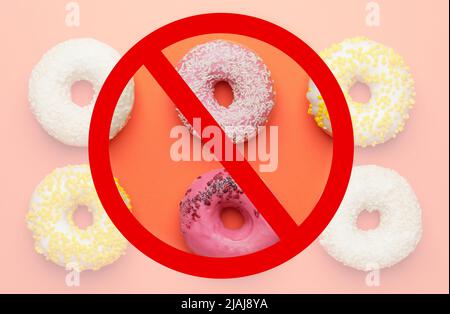 Ciambelle dolci e cartello di divieto su sfondo arancione, vista dall'alto Foto Stock