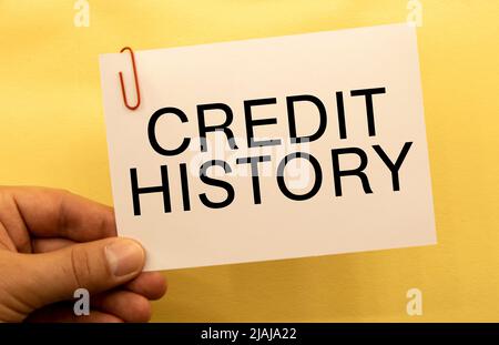 Storia del credito. Testo su carta bianca su sfondo tavola in legno. Foto Stock