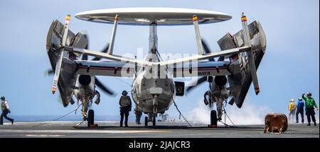 220530-N-DW158-1036 NAVIGAZIONE MARITTIMA FILIPPINA (30 maggio 2022) i marinai effettuano controlli di sicurezza su un e-2D Hawkeye, attaccato al Tigertails of Airborne Early Warning Squadron (VAW) 125, sul ponte di volo dell'unica portaerei della Marina statunitense USS Ronald Reagan (CVN 76). E-2D Hawkeyes esegue missioni tattiche di allerta aerea per fornire informazioni al gruppo di sciopero mentre pianifica ed esegue le operazioni. Ronald Reagan, l'ammiraglia del Carrier Strike Group 5, fornisce una forza pronta per i combattimenti che protegge e difende gli Stati Uniti, e sostiene alleanze, partnership e colletti Foto Stock