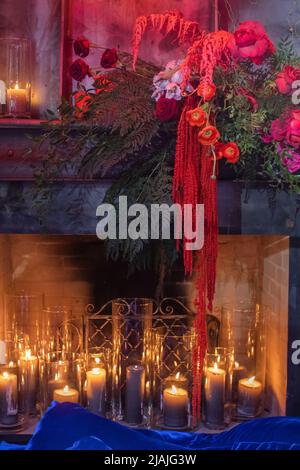 Fiori luminosi vicino al camino con candele. Foto Stock