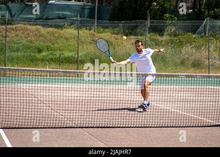 Giocatore di tennis che esegue un tiro di caduta sul campo. Foto Stock