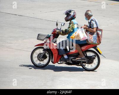 SAMUT PRAKAN, THAILANDIA, Apr 02 2022, Un tassista su una moto con un uomo più anziano. Il mototaxi porta un passeggero Foto Stock