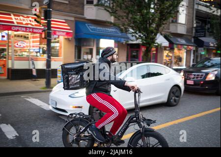 I motociclisti che si consegnano cibo in bici elettriche attraversano il quartiere di VancouverÕs West End di notte. Vancouver, British Columbia, Canada. Foto Stock