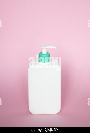 Grande bottiglia di plastica bianca con dispenser a pompa come contenitore per liquidi per gel, lozione, crema, shampoo, schiuma da bagno su sfondo rosa. Foto Stock