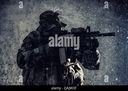 Comando combattente con fucile d'assalto, sneaking nelle tenebre pronto a combattere. Foto Stock