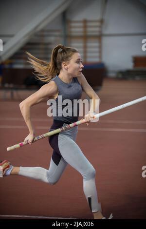 Paletto a volta interno - giovane donna vestita che corre con un palo nelle mani Foto Stock