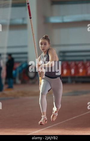 Palo che vaulting indoor - giovane donna piuttosto sportiva che corre con un palo nelle sue mani Foto Stock