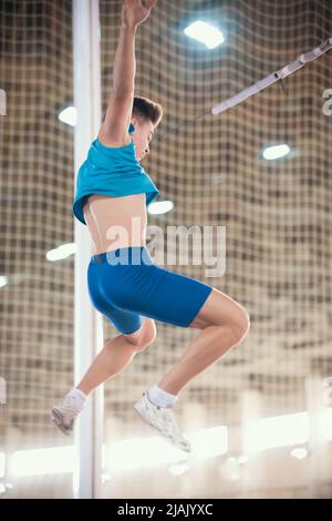 Palo che vaulting indoor - giovane uomo vestito che cade dopo il salto Foto Stock