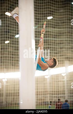 Pole vaulting training - giovane uomo in forma che salta sopra il bar Foto Stock