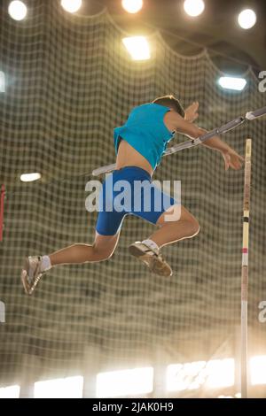 Pole Vault di allenamento nello stadio sportivo - giovane uomo in forma che cade dopo il salto Foto Stock