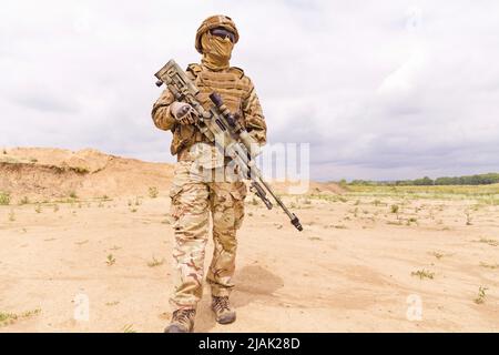 Soldati delle forze speciali equipaggiati e armati con fucile da cecchino in piedi nel deserto. Foto Stock