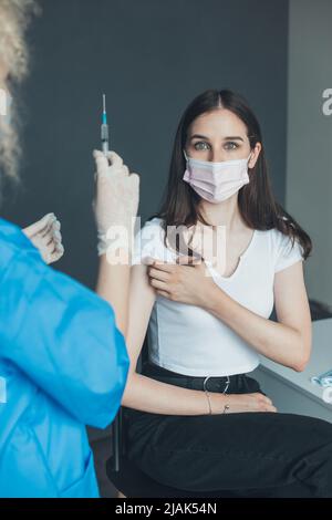 Paziente caucasico che si prepara a vaccinarsi contro l'iniezione di coronavirus, da un medico in un ospedale. Immunizzazione. Vaccinazione influenzale iniezione Foto Stock