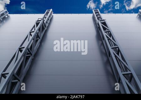 Un'alta parete di metallo che racchiude sorretta da strutture saldate su sfondo blu cielo Foto Stock