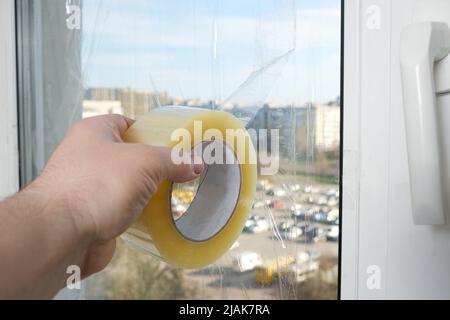 Sigillare le finestre con nastro adesivo durante la guerra in Ucraina per prevenire la formazione di molti frammenti durante l'ondata di esplosione Foto Stock