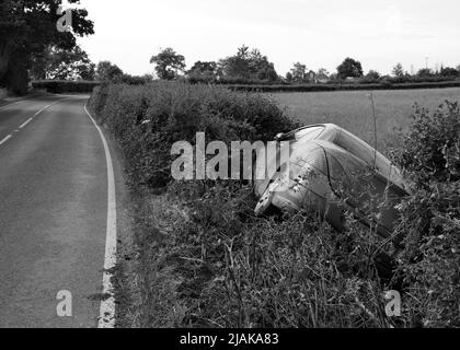 Maggio 2022 - Peugeot auto in un fosso accanto a una strada rurale prima cosa al mattino dopo un fine settimana Foto Stock