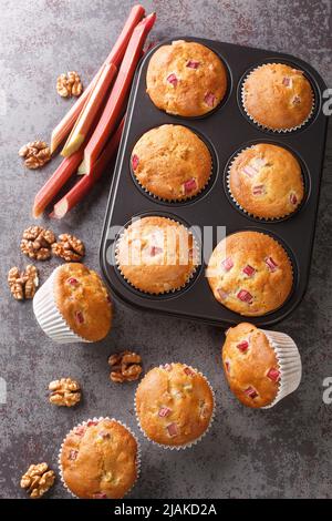 Muffin al rabarbaro con noci in primo piano in una teglia da forno sul tavolo. Vista dall'alto verticale Foto Stock