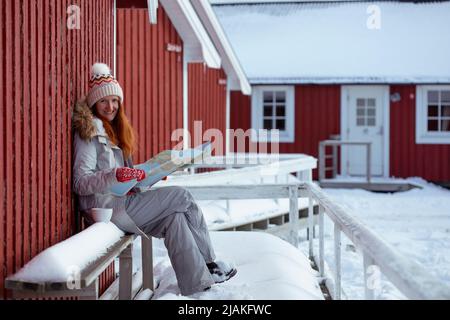 Ragazza turistica si siede vicino rorbu con una mappa a isole Lofoten. Norvegia Foto Stock