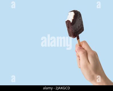 Teen-ager che tiene il gelato eskimo su sfondo azzurro chiaro. Foto Stock