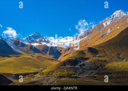 Montagne illuminate dal sole contro il cielo blu Foto Stock