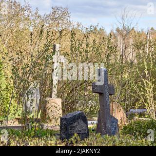 Antica croce di cemento nel cimitero coperto di muschio. Giorno di sole. Foto Stock