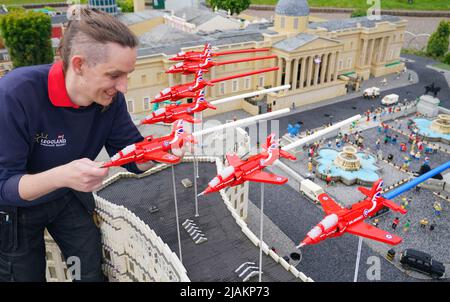 Model Maker Freya Groom mette in mostra uno dei nove modelli LEGO Red Arrow che fanno parte del Platinum Jubilee presentato oggi al LEGOLAND Windsor Resort. La scena della freccia rossa ha impiegato 33 ore per costruire un modello. Ogni piano è di 7,5 cm x 30 cm e ha un'apertura alare di 21,5cm ed è composto da 206 mattoni. LEGOLAND Windsor Resort ha presentato oggi i suoi modelli di ispirazione regale per celebrare il Giubileo del platino della Regina. Il numero complessivo di mattoni utilizzati è stato di 18.001 e i modelli hanno impiegato un totale di 281,5 ore per finire. L'esposizione include anche una festa di strada e scena picnic così come minia Foto Stock