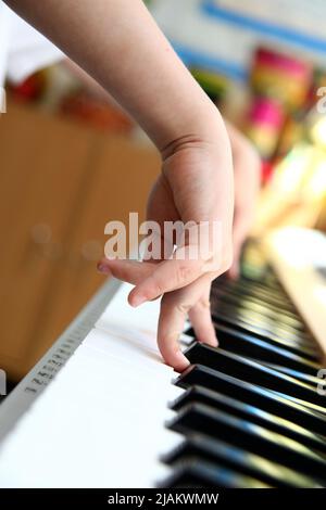 Primo piano di un bambino che suona le mani di un pianoforte Foto Stock