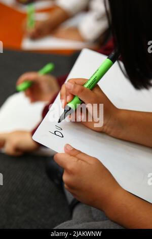 Primo piano di una mano di bambini che pratica la scrittura a mano a scuola Foto Stock