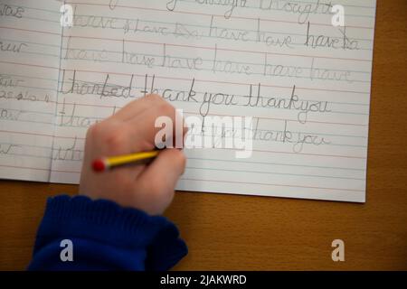 Primo piano di una mano di bambini che pratica la scrittura a mano a scuola Foto Stock