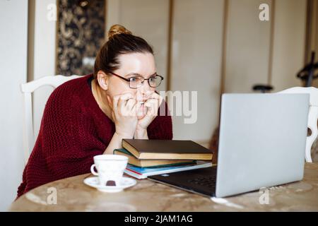 Donna stanca e arrabbiata che usa un notebook, offerte online, lavoro remoto a casa. Internet a bassa velocità, download. Problemi di lavoro Foto Stock