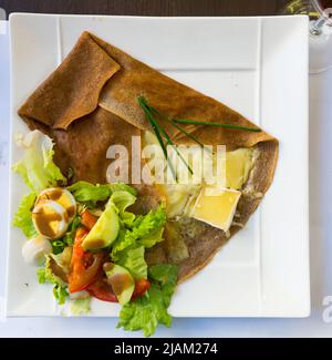 Frittella fritta con formaggio fuso e insalata, piatto di cucina francese Foto Stock