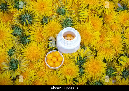 Vitamine in dente di leone. Una bottiglia con pillole gialle in fiori di dente di leone, primo piano Foto Stock