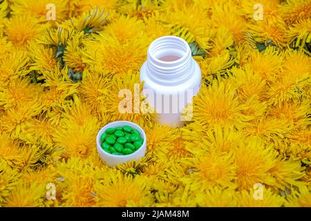 Vitamine in dente di leone. Una bottiglia con pillole verdi in fiori di dente di leone, primo piano Foto Stock