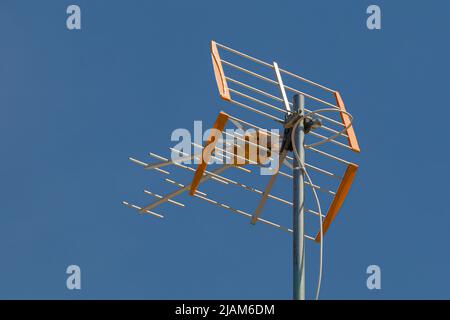 antenna televisiva su un tetto di fronte a un cielo blu Foto Stock