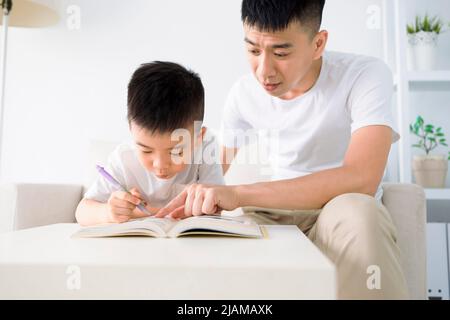 Padre aiutando il bambino a fare i compiti a casa Foto Stock