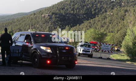 New Mexicoon 21 maggio 2022, i camion e il personale dei vigili del fuoco lasciano le loro posizioni di stanza nel canyon superiore di Pecos e si dirigono per il loro cambio di turno al vicino campo dei vigili del fuoco situato nella città di Pecos. Un ufficiale della Patrol del New Mexico equipaggia un blocco di strada a. Impedisca a tutti tranne i combattenti del fuoco di procedere sulla strada del canyon, New Mexico state Highway 63. (Foto di Steve Clevenger/Sipa USA) Foto Stock