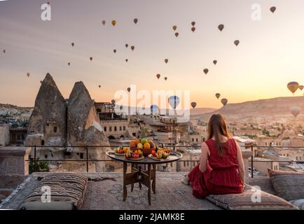 Ragazza in abito rosso guarda palloncini d'aria calda sopra Cappadocia Foto Stock