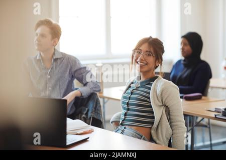 Ritratto di giovane studentessa sorridente seduta in aula Foto Stock