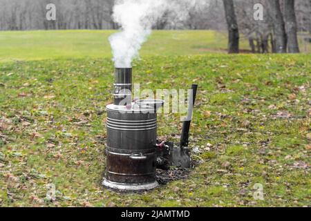 Samovar fumare e bruciare sull'erba in natura. Per tè e caffè in campeggio e pic-nic Foto Stock