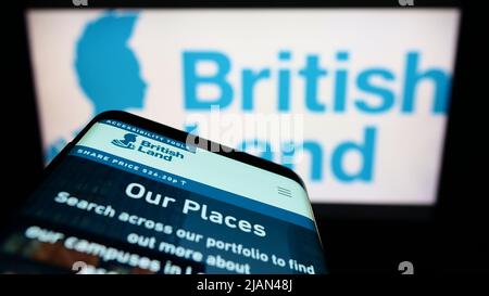Telefono cellulare con pagina web della società The British Land Company plc sullo schermo di fronte al logo business. Mettere a fuoco sulla parte superiore sinistra del display del telefono. Foto Stock