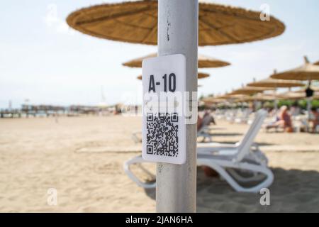 Codice QR sulla pole sulla spiaggia sfocata. Codice QR con numero sedile A10 per menu di selezione Foto Stock