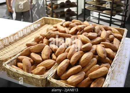 panetteria industriale per la produzione di pane e baguette appena sfornate in cesti di vimini pronti per la vendita dal panettiere Foto Stock