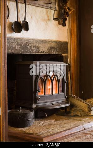Ferro di ghisa nera stufa a legna su camino focolare in cucina all'interno vecchio circa 1840 Canadiana casolare stile fieldstone casa. Foto Stock
