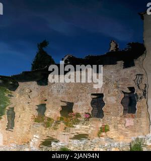 Vista in forma quadrata di edifici in pietra color miele che si riflettono nelle calde acque termali vulcaniche che sgorgano nella vasca da bagno di Santa Caterina del 16th secolo, una piscina rettangolare nel centro di bagno Vignoni, Toscana, Italia. Le proprietà lenitive e curative dell'acqua fumante sono state apprezzate da Etruschi, Romani, Santa Caterina da Siena, il governatore mediceo Lorenzo il magnifico, Papa Pio II, lo scrittore Charles Dickens e il Marchese di Sade. Foto Stock