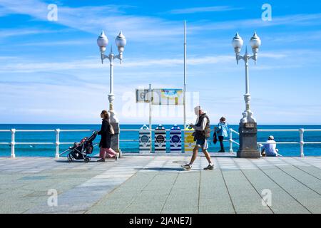 Persone che camminano sul lungomare di San Lorenzo Gijon durante una giornata luminosa con il mare sullo sfondo. Foto Stock