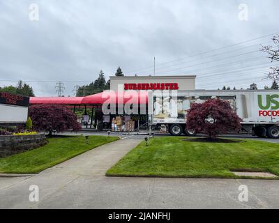 Mill Creek, WA USA - circa Maggio 2022: Vista sulla strada della parte anteriore di un ristorante di fast food Burgermaster mentre ricevono un servizio di consegna di cibo. Foto Stock