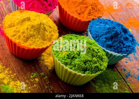 Polvere di Holi colorata in tazze primo piano. Colori luminosi per il festival indiano holi in pentole di argilla. Messa a fuoco selettiva. Sfondo nero, vista dall'alto Foto Stock