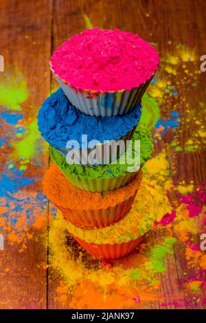 Polvere di Holi colorata in tazze su un tavolo bianco rustico in legno. Vista dall'alto con spazio di copia Foto Stock